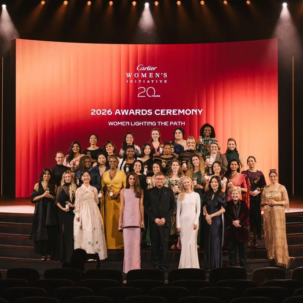 The 2026 fellows of the Cartier Women's Initiative on stage during the 20th-anniversary Awards ceremony, in front of a Cartier-branded red backdrop reading 'Women Lighting the Path'.