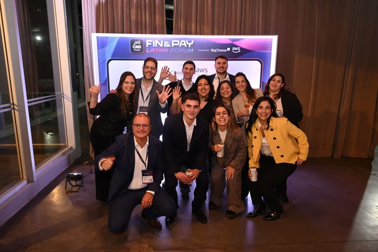 Group photo of around eleven people in business attire posing energetically in front of a 'FIN & PAY LATAM FORUM' backdrop at CMS People's Fin & Pay Latam Forum 2026 in Buenos Aires, sponsored by BigCheese and AWS.