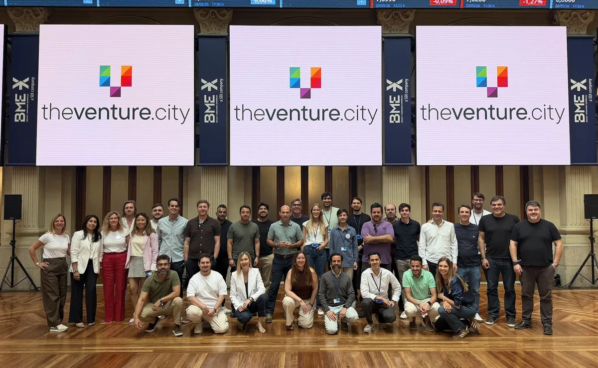 Group photo of attendees on stage at TheVentureCity Summit 2026 at the Madrid Stock Exchange, with three large theventure.city screens behind them.